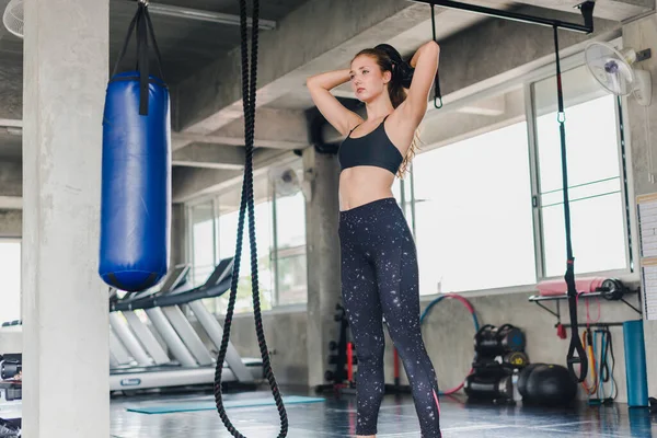 Spor salonunda egzersiz yapmak için kum torbalarını yumruklayan bayan sporcular. Siyah spor giyer. Ve boks eldiveni giy.