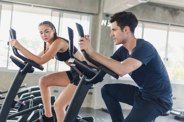 Male and female athletes talk about exercise, cycling in the gym. They wear sportswear to exercise.