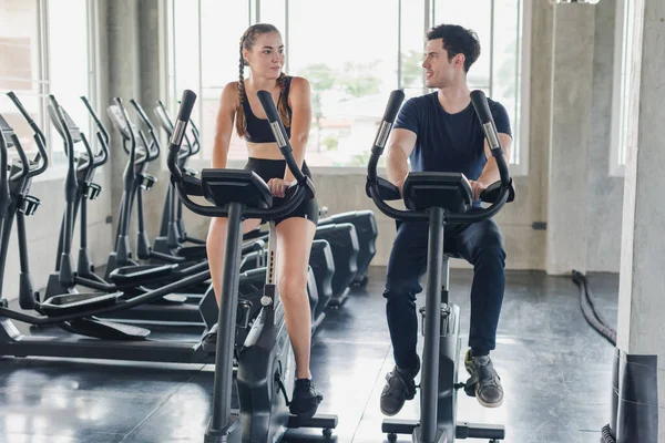 Male and female athletes talk about exercise, cycling in the gym. They wear sportswear to exercise.