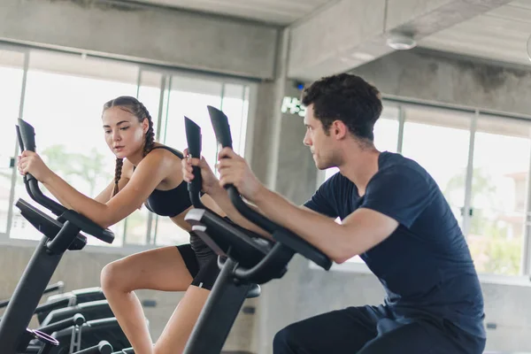 Male and female athletes talk about exercise, cycling in the gym. They wear sportswear to exercise.