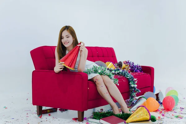 Asian woman in white dress Sitting on the red sofa There are things for decoration during Christmas and New Year.