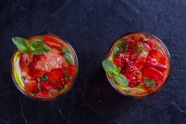 Çilek mojito çilek, limon, nane ve buz, siyah arka plan ile kokteyl. Yaz berry kokteyl. Yukarıda görmek, en iyi stüdyo vurdu