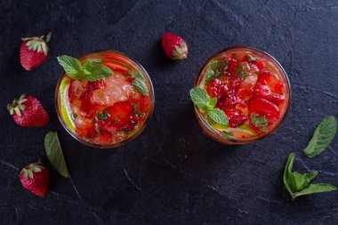 Çilek mojito çilek, limon, nane ve buz, siyah arka plan ile kokteyl. Yaz berry kokteyl. Yukarıda görmek, en iyi stüdyo vurdu