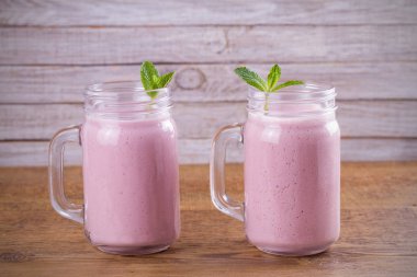 Pembe çilek milkshake veya kokteyl iki kadeh. Ahşap masa üzerinde çilek muz smoothie. Yatay