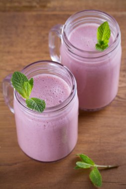 Pembe çilek milkshake veya kokteyl iki kadeh. Ahşap masa üzerinde çilek muz smoothie. dikey