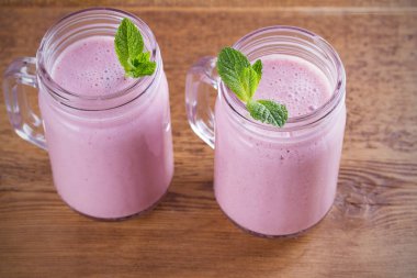 Pembe çilek milkshake veya kokteyl iki kadeh. Ahşap masa üzerinde çilek muz smoothie. Yatay