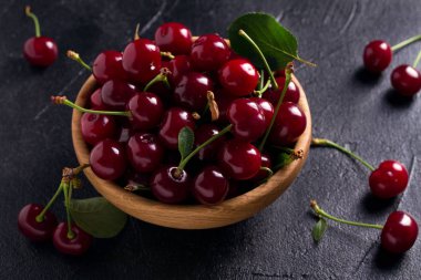 Siyah arka plan üzerine ahşap kase taze kiraz. Taze olgun tatlı kiraz