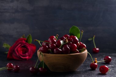 Siyah arka plan üzerine ahşap kase taze kiraz. Taze olgun tatlı kiraz