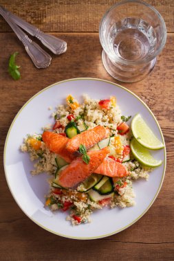 Domates kuskus, kabak ve kireç beyaz tabakta ile kavrulmuş somon balık. Tepegöz, dikey