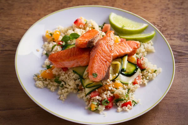 Domates kuskus, kabak ve kireç beyaz tabakta ile kavrulmuş somon balık. Yatay