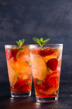 Çilek mojito çilek, limon ve nane ile kokteyl. Yaz meyve siyah arka plan üzerine kokteyl. metin, dikey için yer