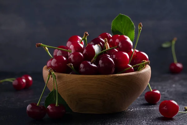 Fresh cherry in wooden bowl on black background. Fresh ripe red sweet cherries. horizontal