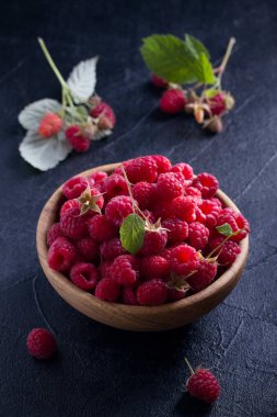 Ahududu siyah arka plan üzerine ahşap kase. Taze olgun tatlı çilek, sağlıklı yemek. Yaz meyveleri. dikey