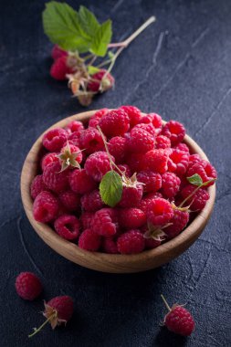 Ahududu siyah arka plan üzerine ahşap kase. Taze olgun tatlı çilek, sağlıklı yemek. Yaz meyveleri. dikey