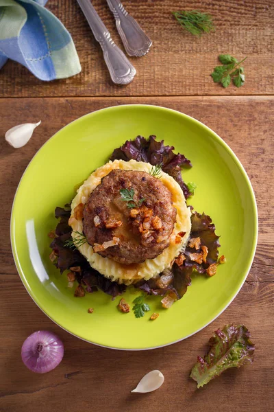Lezzetli burger veya patty marul, patates püresi ile servis ile tuzlu karamelize soğan. Tepegöz, dikey