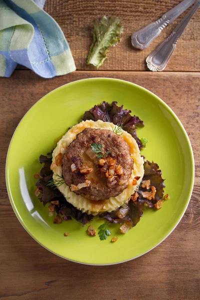 Lezzetli burger veya patty marul, patates püresi ile servis ile tuzlu karamelize soğan. Tepegöz, dikey