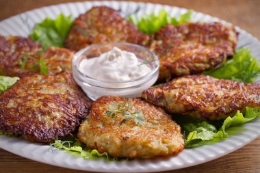 Patates börek, latkeler, draniki, kıymalı patates - birçok ülkede popüler çanak. Beyaz plaka, ahşap masa üzerinde sebze krep. Yatay