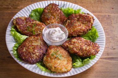 Patates börek, latkeler, draniki, kıymalı patates - birçok ülkede popüler çanak. Beyaz plaka, ahşap masa üzerinde sebze krep. Yatay