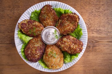 Patates börek, latkeler, draniki, kıymalı patates - birçok ülkede popüler çanak. Beyaz plaka, ahşap masa üzerinde sebze krep. Tepegöz, yatay