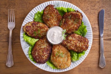 Patates börek, latkeler, draniki, kıymalı patates - birçok ülkede popüler çanak. Beyaz plaka, ahşap masa üzerinde sebze krep. Tepegöz, yatay