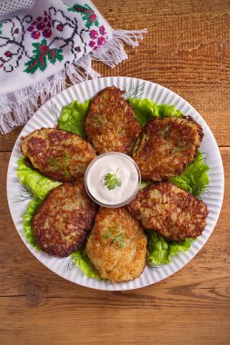 Patates börek, latkeler, draniki, kıymalı patates - birçok ülkede popüler çanak. Beyaz plaka, ahşap masa üzerinde sebze krep. Tepegöz, dikey