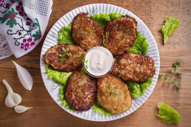Patates börek, latkeler, draniki, kıymalı patates - birçok ülkede popüler çanak. Beyaz plaka, ahşap masa üzerinde sebze krep. Tepegöz, yatay