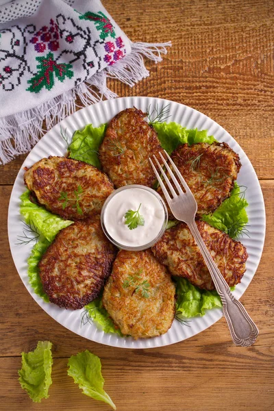 Patates börek, latkeler, draniki, kıymalı patates - birçok ülkede popüler çanak. Beyaz plaka, ahşap masa üzerinde sebze krep. Tepegöz, dikey