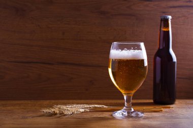 Cam ve şişe bira, kulakları arpa ahşap masa üzerinde. Ale. Metin için yer