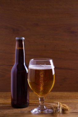 Cam ve şişe bira, kulakları arpa ahşap masa üzerinde. Ale. Metin için yer