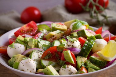 Avokado, domates, salatalık salatası ile mozzarella peyniri ahşap masa üzerinde beyaz kase. Yatay
