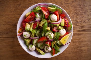 Avokado, domates, salatalık salatası ile mozzarella peyniri ahşap masa üzerinde beyaz kase. Tepegöz, yatay