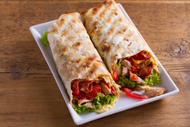 Tavuklu Sezar salata pastırma, domates, marul ve peynir ile tamamladı. Tortilla, burrito, bükülmüş sandviç rulo