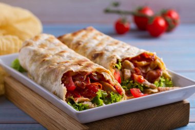 Chicken caesar salad wraps with bacon, tomatoes, lettuce and cheese. Tortilla, burritos, sandwiches twisted rolls clipart