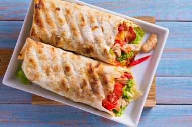 Tavuklu Sezar salata pastırma, domates, marul ve peynir ile tamamladı. Tortilla, burrito, bükülmüş sandviç rulo. Yukarıdan görüntülemek, top