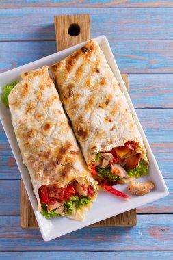 Tavuklu Sezar salata pastırma, domates, marul ve peynir ile tamamladı. Tortilla, burrito, bükülmüş sandviç rulo. Yukarıdan görüntülemek, top