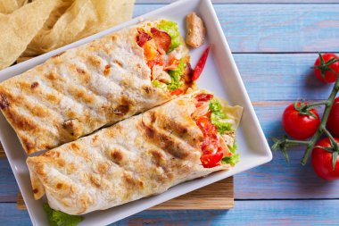 Tavuklu Sezar salata pastırma, domates, marul ve peynir ile tamamladı. Tortilla, burrito, bükülmüş sandviç rulo. Yukarıdan görüntülemek, top