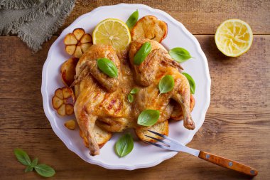 Bütün tavuk limon, fesleğen ve sarımsak beyaz plaka, ahşap masa üzerinde kızarmış ekmek üzerinde. Tepegöz, yatay
