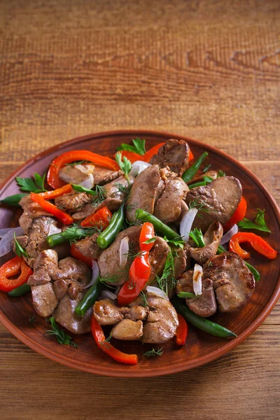 Chicken liver with red paprika, green beans and onion. Sauteed liver with vegetables on a plate. vertical