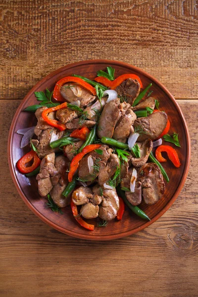 Chicken liver with red paprika, green beans and onion. Sauteed liver with vegetables on a plate. overhead, vertical