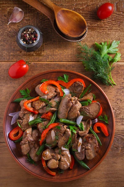 Chicken liver with red paprika, green beans and onion. Sauteed liver with vegetables on a plate. overhead, vertical