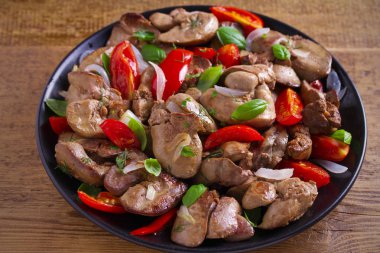 Domates, soğan ve fesleğen siyah plaka, ahşap masa üzerinde tavuk karaciğer. Yatay