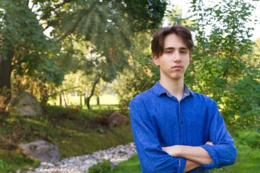 Genç adam kameraya, bakan gülümseyerek. Kot gömlek genç çocuk portresi, silah koruma, portre Park dışında çarpı işareti