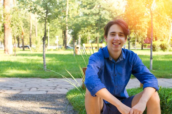 Parkta genç adam dış portresi. Yakışıklı genç gülümseyen 