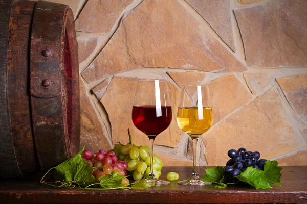 红酒酒窖中的老木桶旁有葡萄红白葡萄酒 — 图库照片