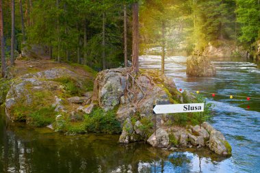 Directional rout sign, arrow in forest on river bank. View of the Telemark Canal with old locks - tourist attraction in Skien, Norway clipart