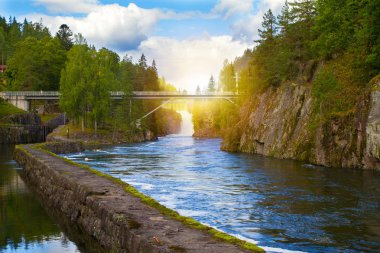 Bridge above the river and waterfall. View of the Telemark Canal with old locks - tourist attraction in Skien, Norway clipart