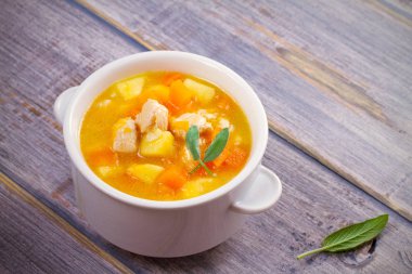 Tavuk, butternut squash, elma, zencefil ve adaçayı ahşap masa üzerinde beyaz kapta güveç. Balkabağı çorbası tavuk. Yatay