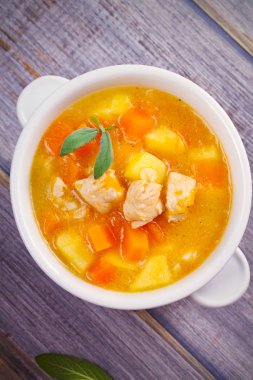 Tavuk, butternut squash, elma, zencefil ve adaçayı ahşap masa üzerinde beyaz kapta güveç. Balkabağı çorbası tavuk. Tepegöz, dikey