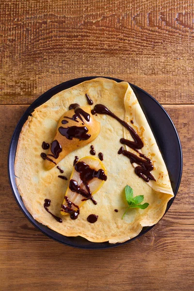 Crepes with baked pear and chocolate. Pancakes with baked pear and chocolate. View from above, top studio shot