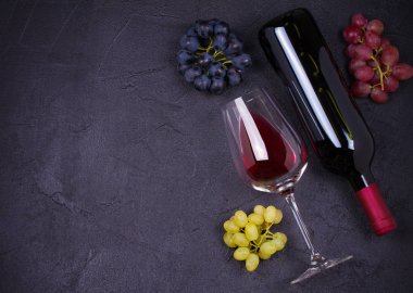 Cam ve şişe şarap üzüm, incir ve siyah taş doku arka plan üzerinde fındık ile. Yukarıda görmek, en iyi stüdyo vurdu